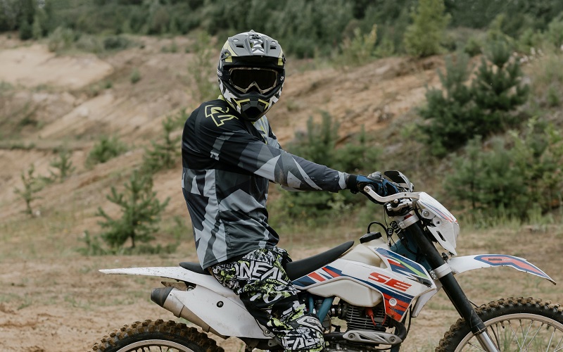 Man sitting on motocross parked in nature